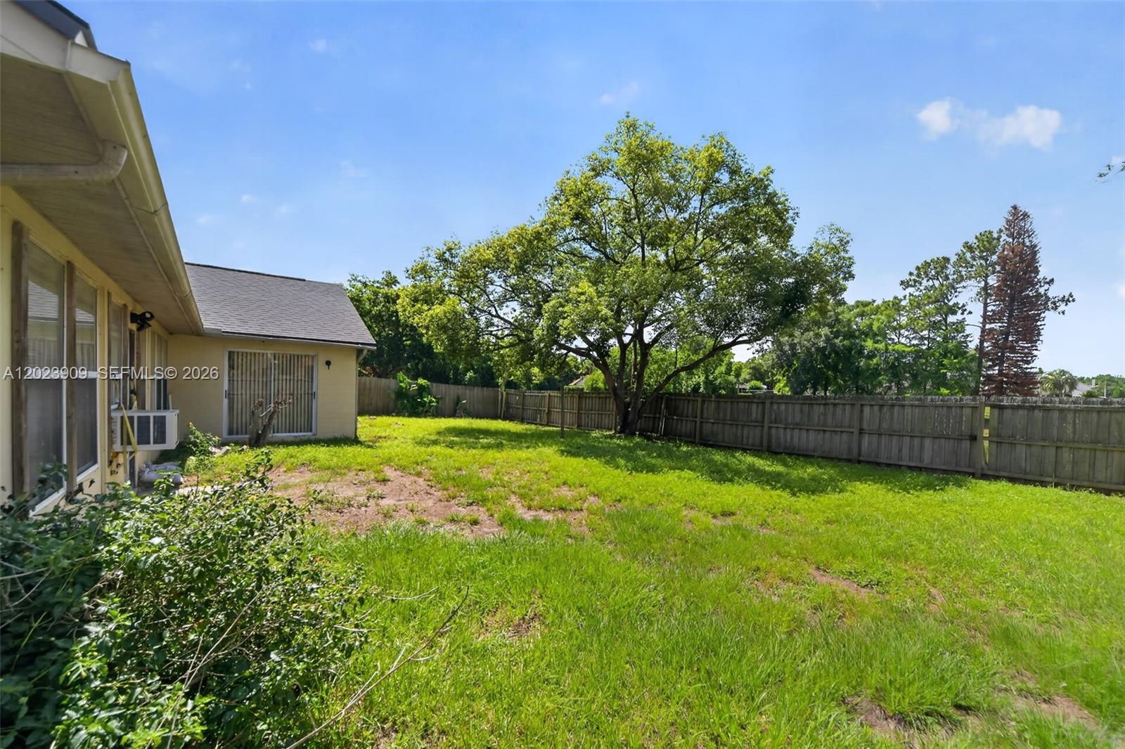 A backyard features a grassy lawn, a large tree, and a wooden privacy fence — 10300 YORKMERE CT, Orlando FL 32817, ORLANDO, FL