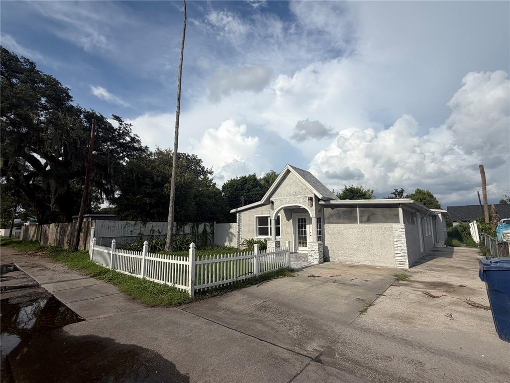 A single-story house with a white picket fence, concrete driveway, and a small front yard — 5103 N 30TH STREET, TAMPA, FL