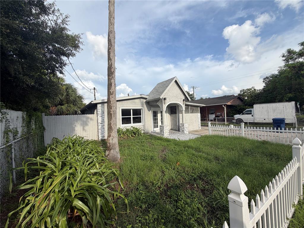 A single-story house with a white picket fence and a tall palm tree in front — 5103 N 30TH STREET, TAMPA, FL