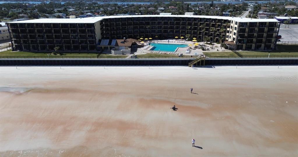 An aerial view shows a multi-story beachfront hotel with a pool and sandy beach — 2301 S ATLANTIC AVENUE UNIT 303, DAYTONA BEACH SHORES, FL