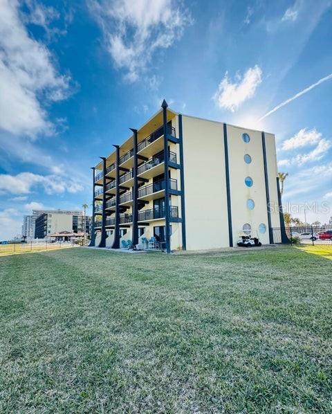 A multi-story apartment building with balconies and circular windows sits behind a grassy lawn — 2301 S ATLANTIC AVENUE UNIT 303, DAYTONA BEACH SHORES, FL
