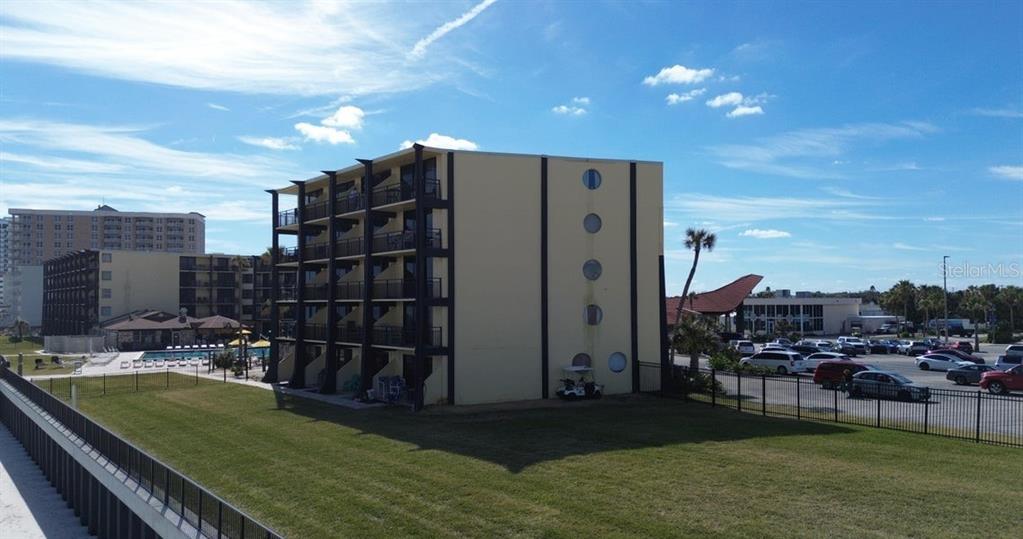 A multi-story apartment building with balconies stands next to a parking lot and lawn — 2301 S ATLANTIC AVENUE UNIT 303, DAYTONA BEACH SHORES, FL