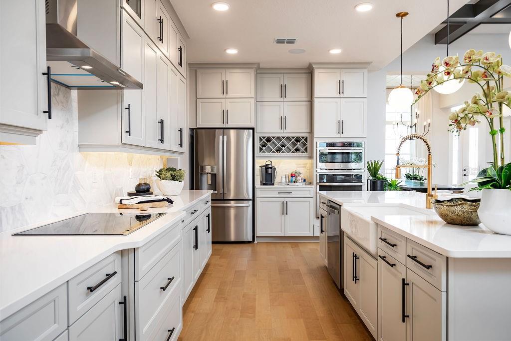 A modern kitchen features light gray cabinets, stainless steel appliances, and a white farmhouse sink — 2739 RAVENCLIFFE TERRACE, OVIEDO, FL