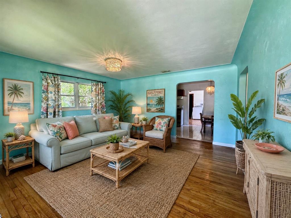 A living room with turquoise walls, a light-colored sofa, wicker furniture, and hardwood floors — 2602 UPTON STREET S, GULFPORT, FL