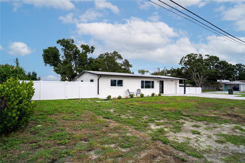 A white single-story house with a garage and a white vinyl fence sits on grass — 12425 RIDGE ROAD, LARGO, FL