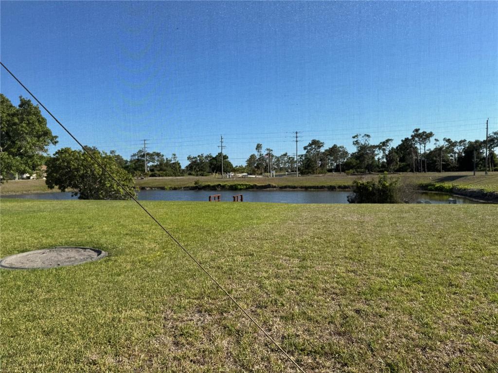 A view of a grassy backyard overlooking a pond under a clear blue sky — 640 BOUNDARY BOULEVARD, ROTONDA WEST, FL
