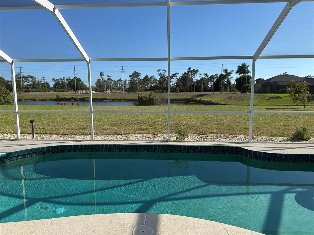 A swimming pool with a screen enclosure overlooks a grassy lawn and a pond — 640 BOUNDARY BOULEVARD, ROTONDA WEST, FL