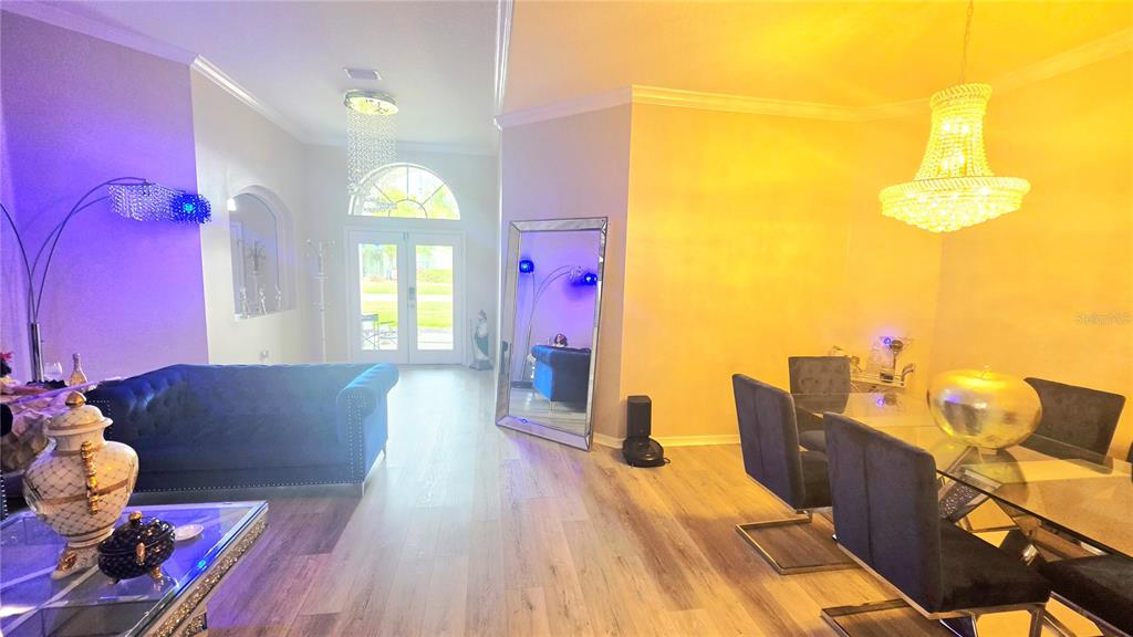 A living and dining area features a blue tufted sofa, glass table, and crystal chandelier — 4205 MAST COURT, LAND O LAKES, FL