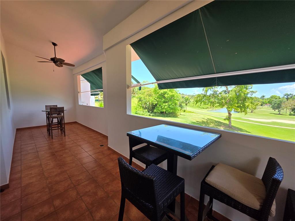 A covered outdoor patio features tile flooring, two dining sets, and a golf course view — 4703 RIO MAR VILLAGE, RIO GRANDE, PR