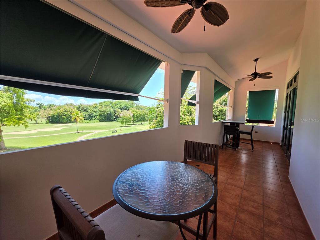 A covered balcony with tile flooring, outdoor furniture, and a view of a golf course — 4703 RIO MAR VILLAGE, RIO GRANDE, PR