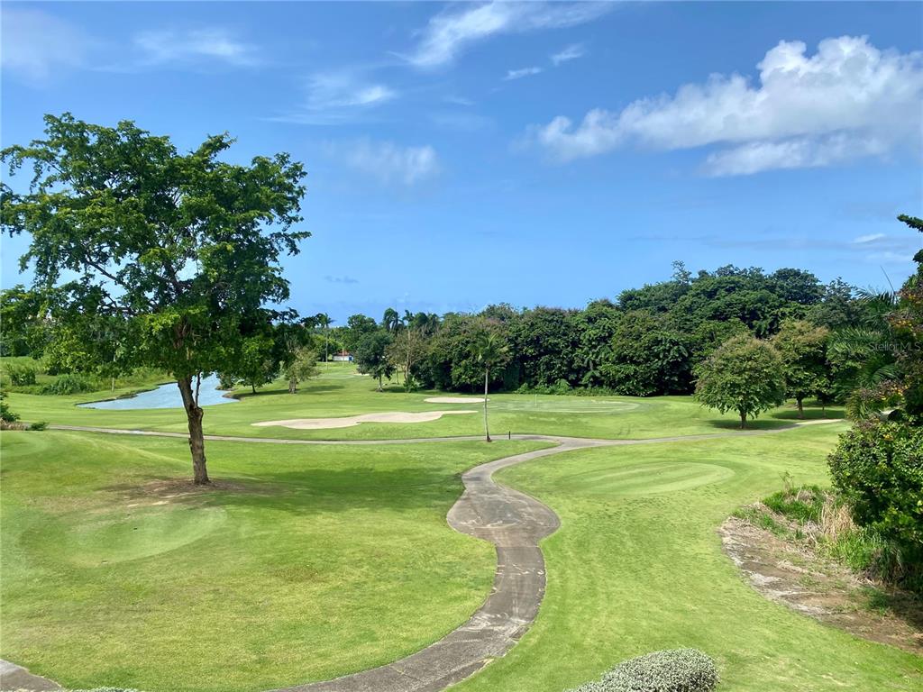 A view of a golf course fairway with a cart path, trees, and a pond — 4703 RIO MAR VILLAGE, RIO GRANDE, PR