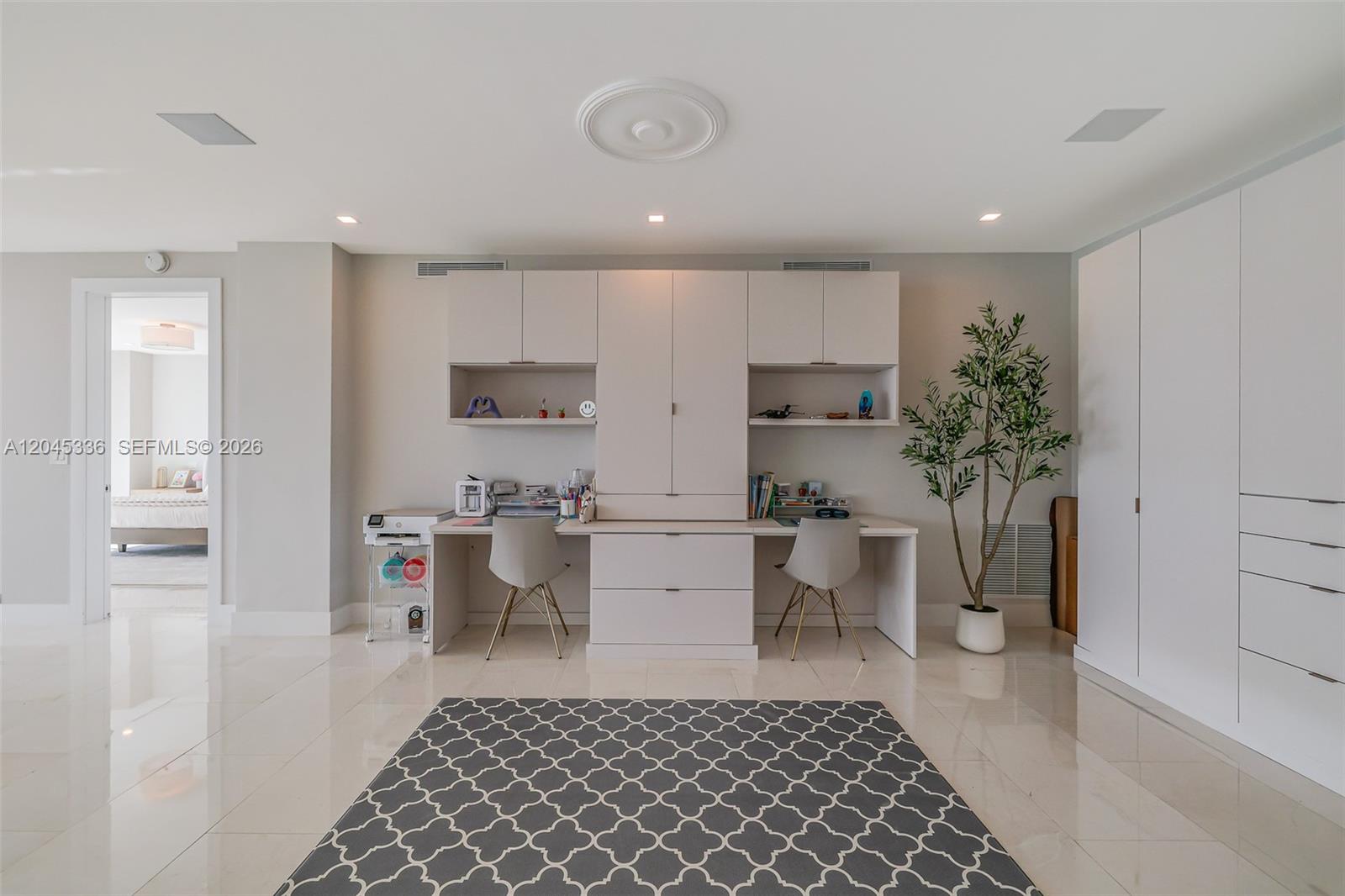 A modern home office features a dual-desk built-in unit, white cabinetry, and a patterned rug — 3400 SW 27th Ave # 802, Miami FL 33133, MIAMI, FL