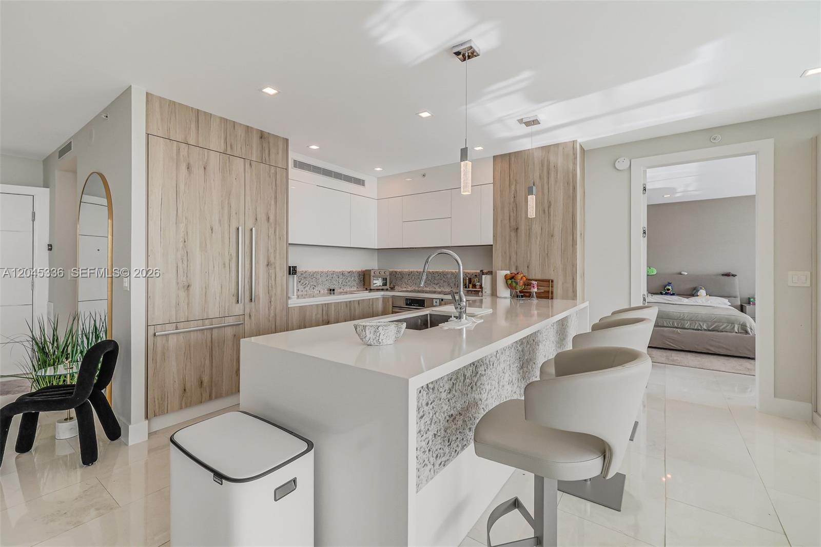 A modern kitchen features light wood cabinetry, white countertops, and a central island with seating — 3400 SW 27th Ave # 802, Miami FL 33133, MIAMI, FL