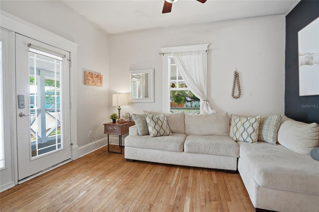 A living room features a light-colored sectional sofa, hardwood floors, and a glass-paned door — 5602 N OLA AVENUE, TAMPA, FL