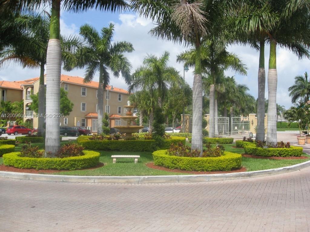 A circular driveway features a central fountain surrounded by manicured hedges and palm trees — 6630 NW 114th AV # 1503, Doral FL 33178, DORAL, FL