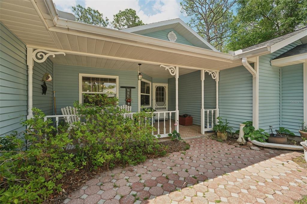 A light blue house features a covered front porch with white railings and brick pavers — 4381 N CAPISTRANO LOOP, BEVERLY HILLS, FL