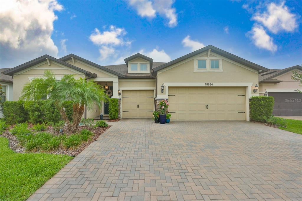 A single-story house features a paved driveway, a three-car garage, and a landscaped front yard — 18824 ALDER GLEN DRIVE, LUTZ, FL