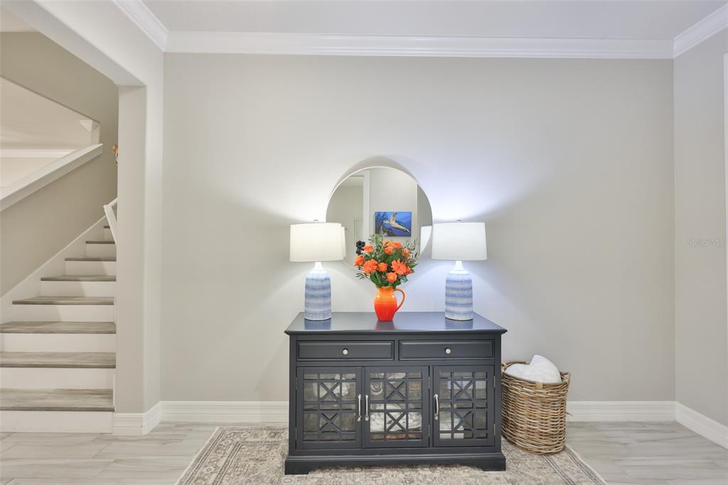 A dark wood console table with two lamps and a mirror sits in a foyer — 18824 ALDER GLEN DRIVE, LUTZ, FL