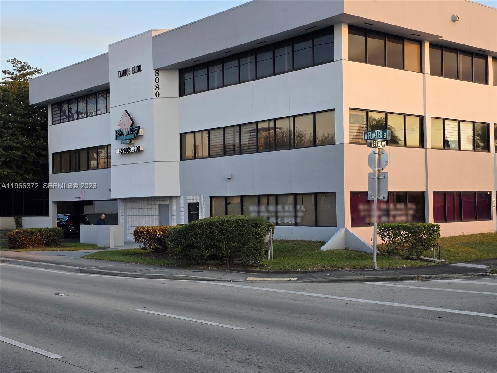 A three-story commercial office building with white walls and dark-tinted windows stands near a street — 8080 W Flagler St, Miami FL 33144, MIAMI, FL