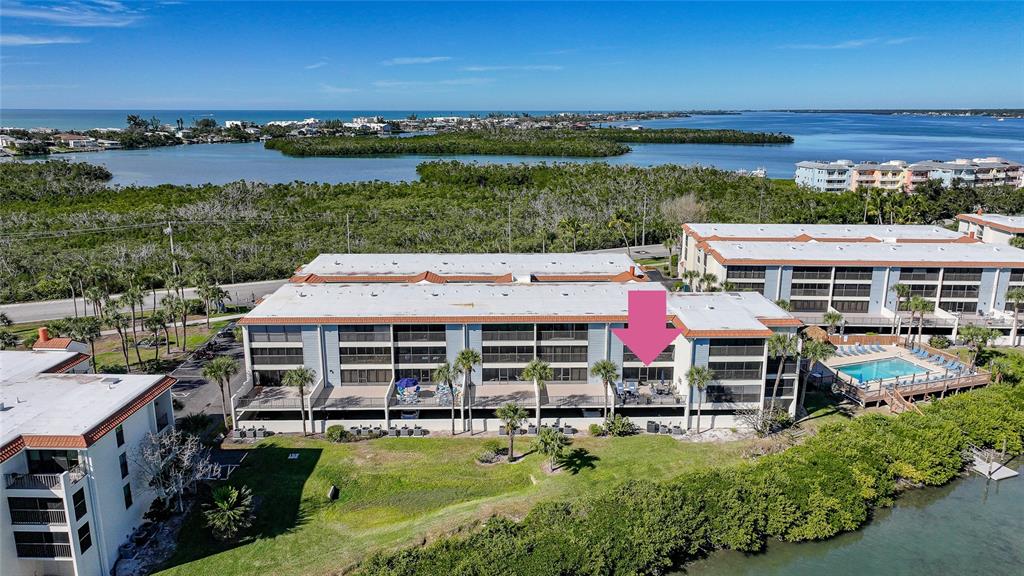 An aerial view shows a multi-story apartment building with a balcony marked by an arrow — 1701 BEACH ROAD UNIT 202, ENGLEWOOD, FL