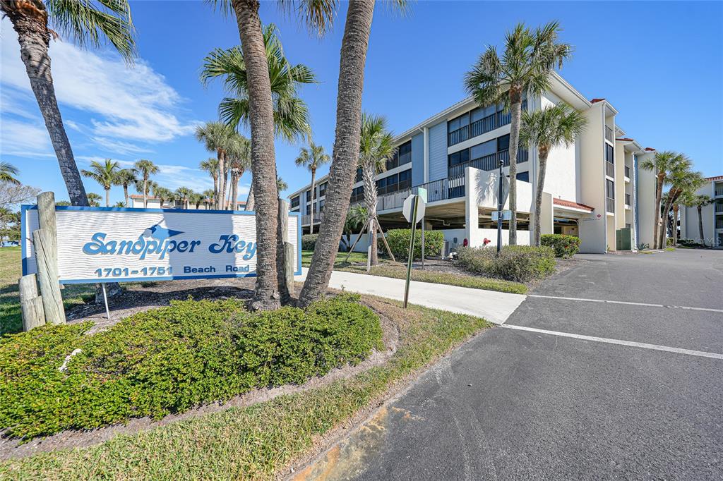 A sign for Sandpiper Key stands in front of a multi-story apartment building with palms — 1701 BEACH ROAD UNIT 202, ENGLEWOOD, FL