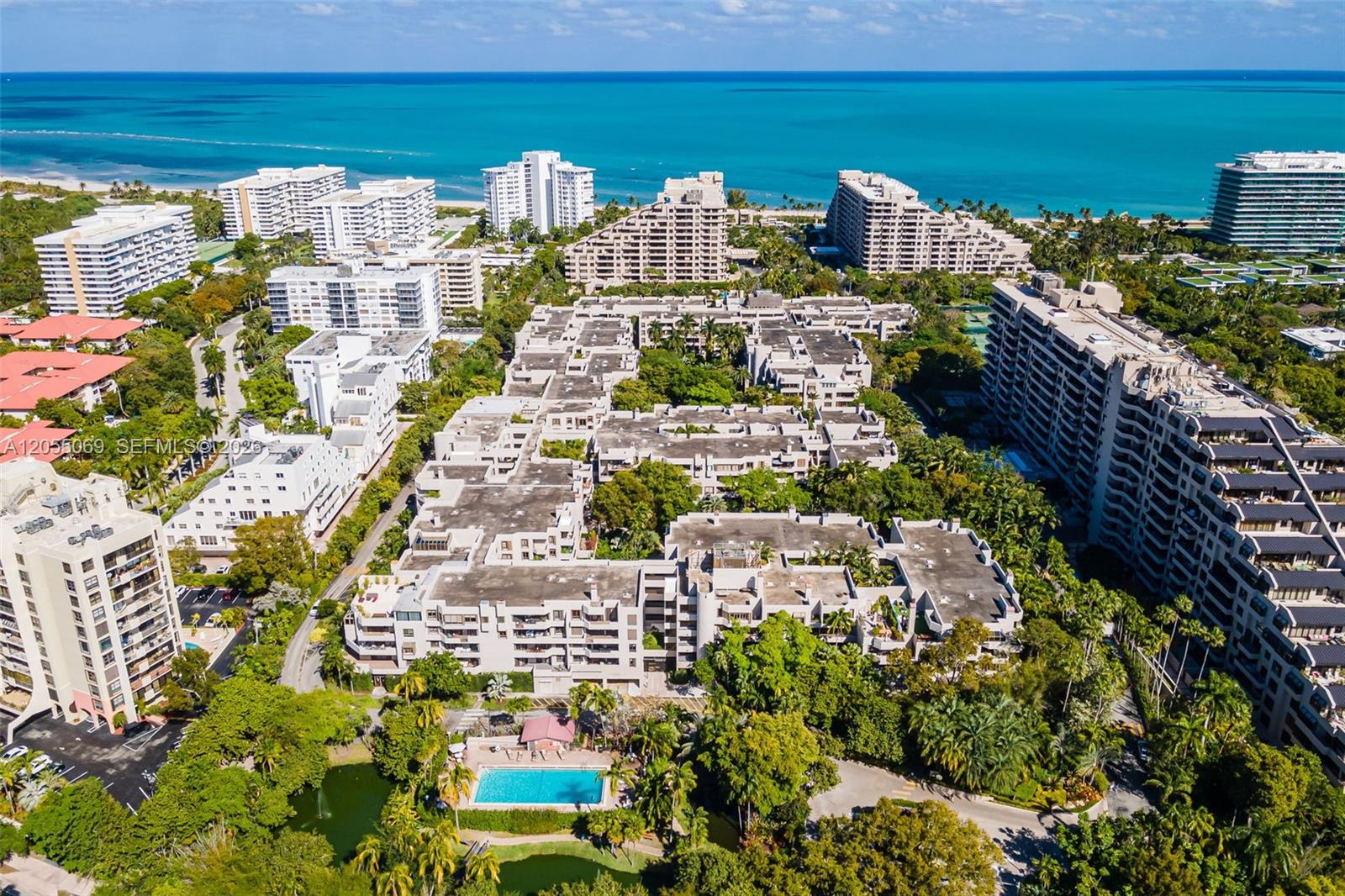 An aerial view shows a large residential complex with a swimming pool and ocean backdrop — 201 Crandon Blvd # 220, Key Biscayne FL 33149, KEY BISCAYNE, FL