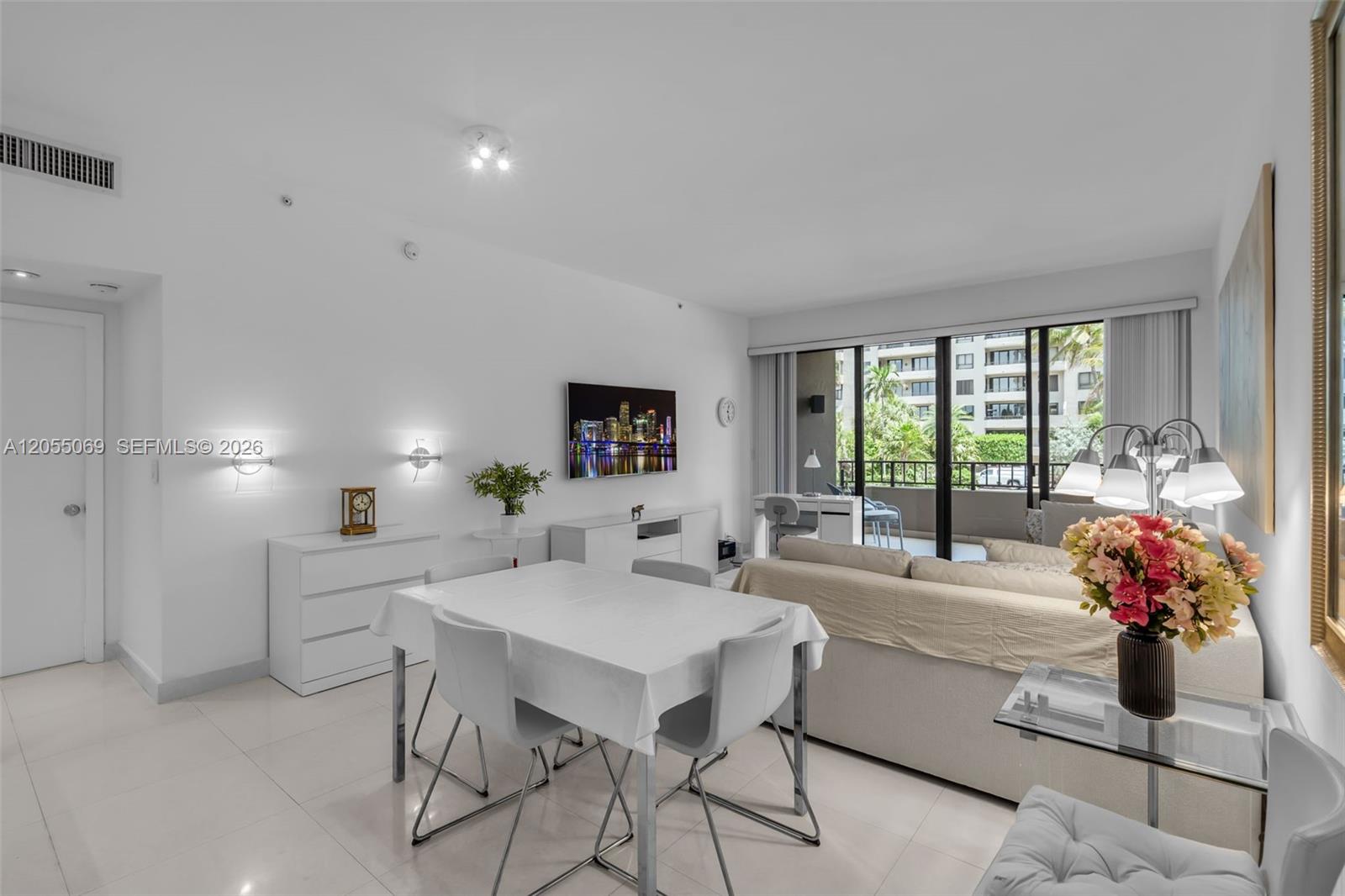 A bright living and dining area features white tile floors, modern furniture, and a balcony — 201 Crandon Blvd # 220, Key Biscayne FL 33149, KEY BISCAYNE, FL