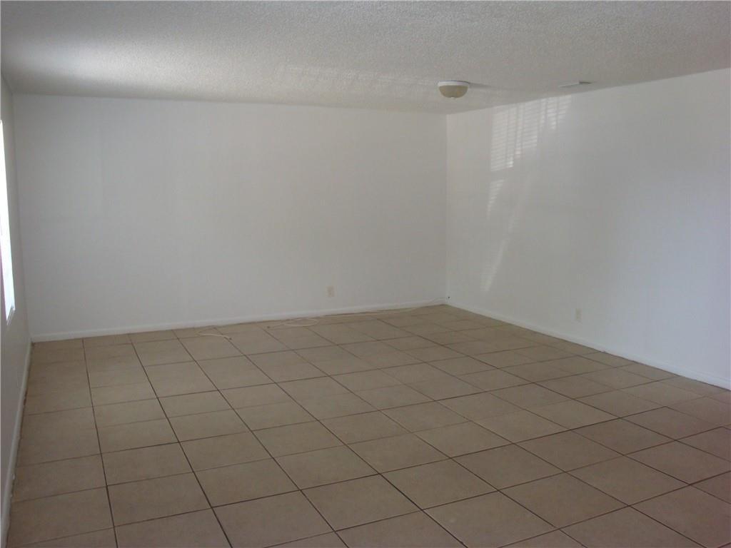 An empty room features white walls, a textured ceiling, and light-colored square floor tiles — 1633 W 28th Street # B, Riviera Beach FL 33404, RIVIERA BEACH, FL
