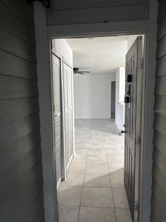 An open front door reveals a tiled entryway leading into a living area with a ceiling fan — 6028 WESTGATE DRIVE UNIT 102, ORLANDO, FL