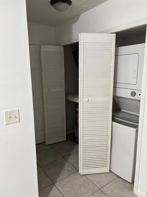 A laundry closet features a stacked washer and dryer unit next to a water heater — 6028 WESTGATE DRIVE UNIT 102, ORLANDO, FL