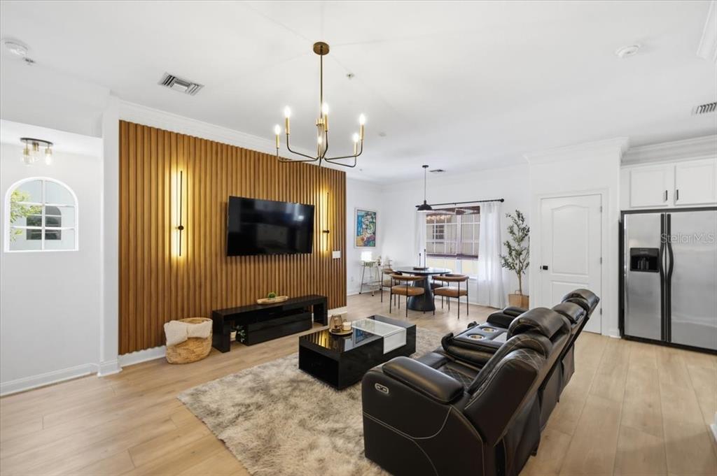 A living room features a wood-slat accent wall with a mounted television and black furniture — 2315 W NORTH A STREET UNIT 3, TAMPA, FL
