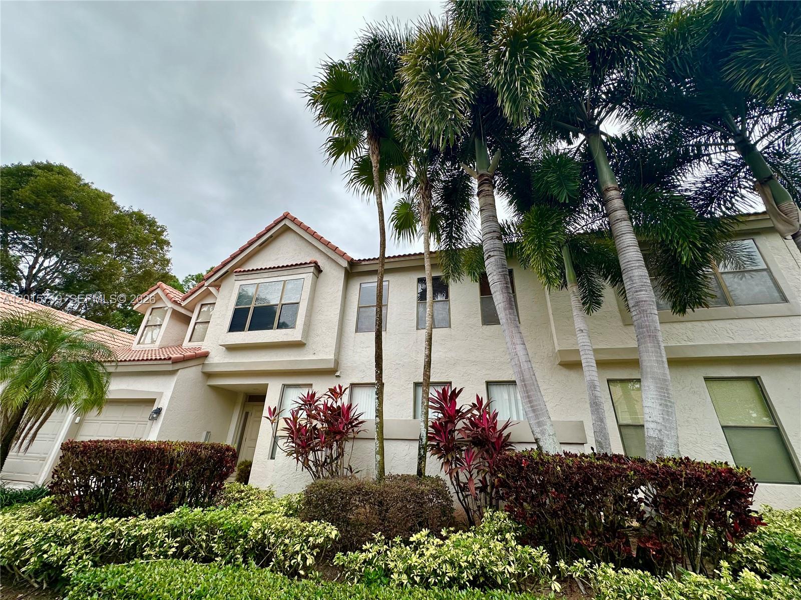 A two-story stucco house features a tiled roof, palm trees, and landscaped bushes — 5790 Coach House Cir, Boca Raton FL 33486, BOCA RATON, FL