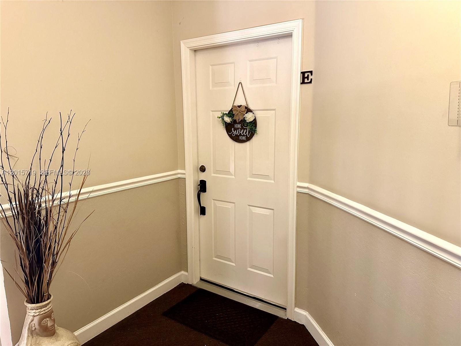 A white door with a decorative sign hangs in a hallway with beige walls — 5790 Coach House Cir, Boca Raton FL 33486, BOCA RATON, FL