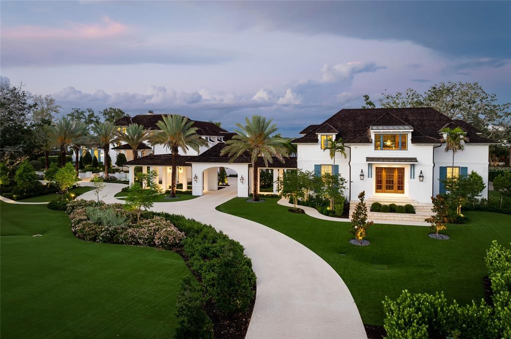 A large white multi-story house with a dark roof and a curved driveway at dusk — 8501 MIDNIGHT PASS ROAD, SARASOTA, FL