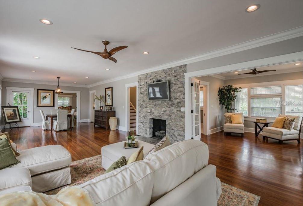 A living room with a stone fireplace, hardwood floors, and an adjacent dining area — 209 13TH AVENUE N, ST PETERSBURG, FL