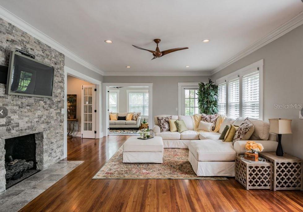 A living room features a stone fireplace, hardwood floors, and a large white sectional sofa — 209 13TH AVENUE N, ST PETERSBURG, FL