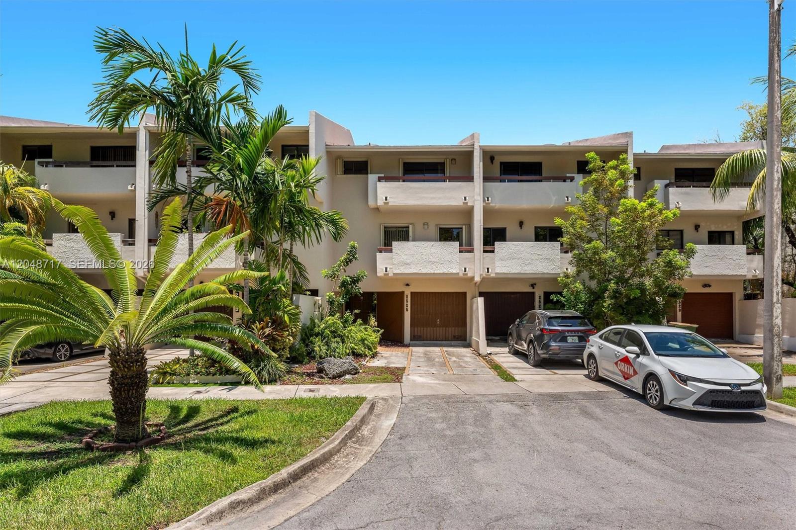 A multi-story townhouse complex features balconies, garage doors, and palm trees in the front yard — 2525 NE 135th St, North Miami FL 33181, NORTH MIAMI, FL