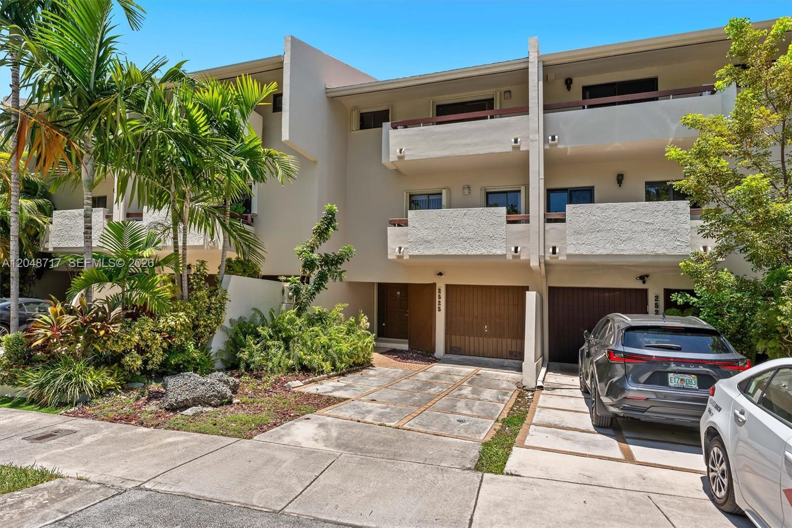 A multi-story townhouse exterior features two garage doors, balconies, and a paved driveway — 2525 NE 135th St, North Miami FL 33181, NORTH MIAMI, FL