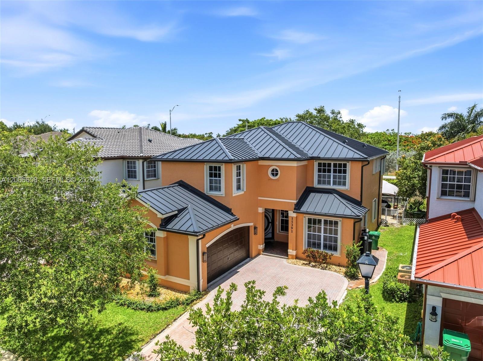 An orange two-story house with a dark metal roof and a brick driveway — 15391 SW 18th St, Miramar FL 33027, MIRAMAR, FL