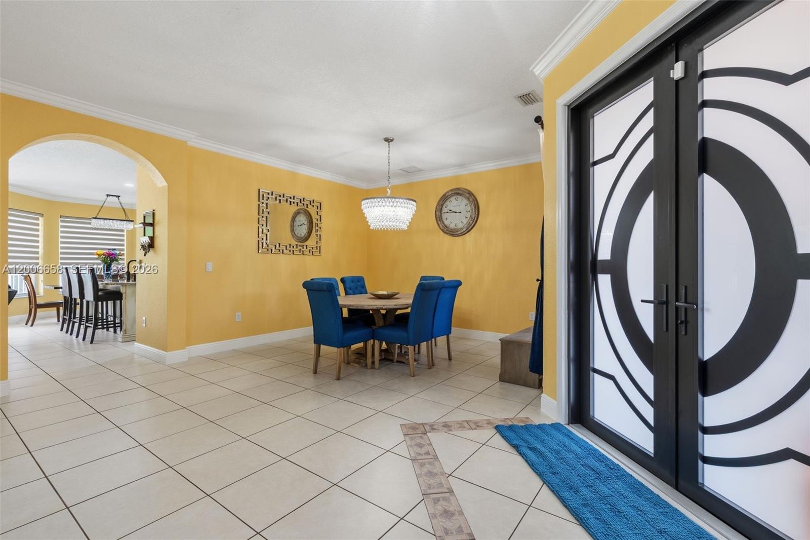 A dining room with yellow walls, blue chairs, a crystal chandelier, and tiled flooring — 15391 SW 18th St, Miramar FL 33027, MIRAMAR, FL