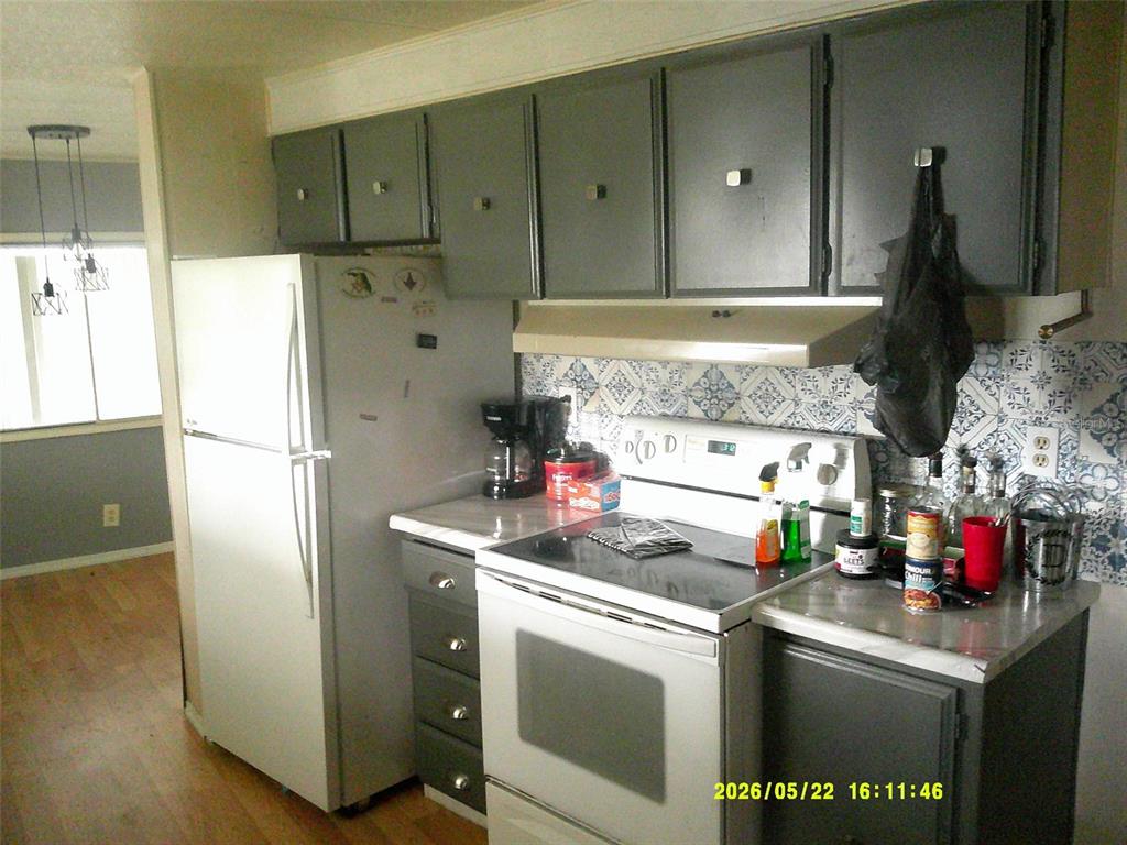 A kitchen features gray cabinets, white appliances, and a blue and white patterned backsplash — 15211 SE 104TH COURT, SUMMERFIELD, FL