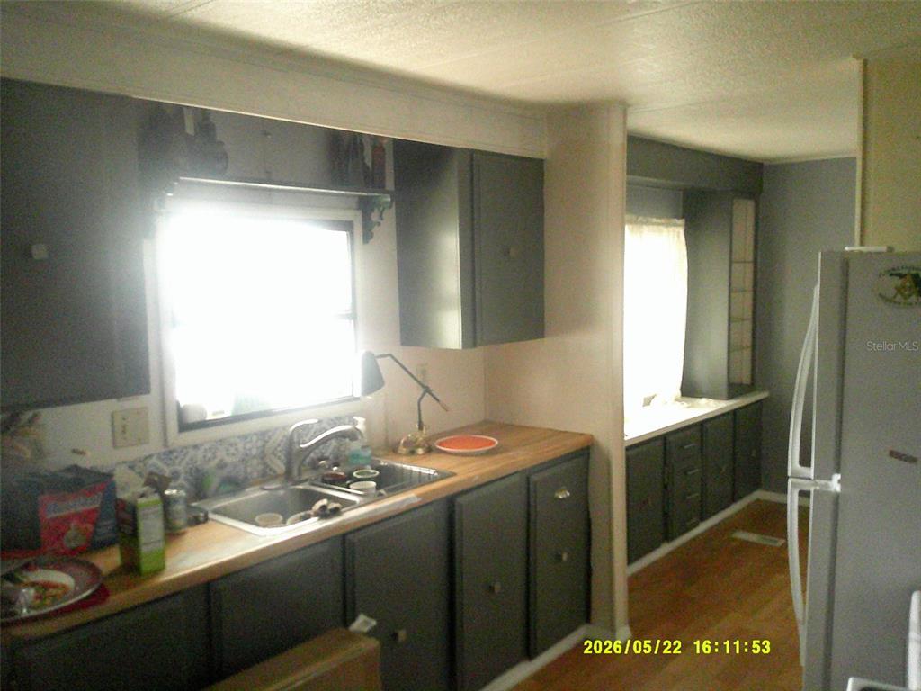 A kitchen features dark grey cabinets, a wood countertop, a stainless steel sink, and appliances — 15211 SE 104TH COURT, SUMMERFIELD, FL