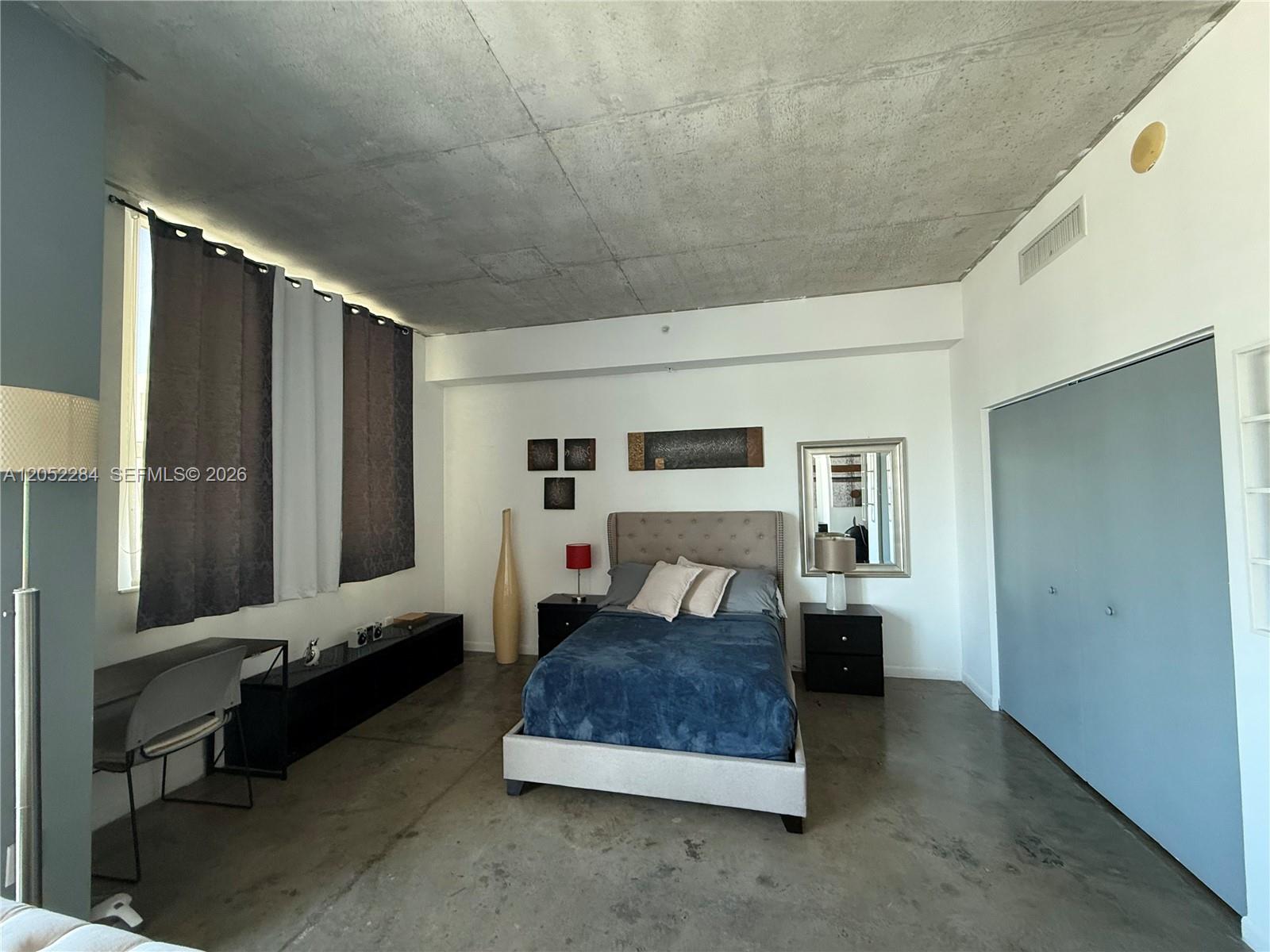 A bedroom features a concrete ceiling, polished concrete floors, and a blue-toned closet door — 133 NE 2nd Ave # 2811, Miami FL 33132, MIAMI, FL