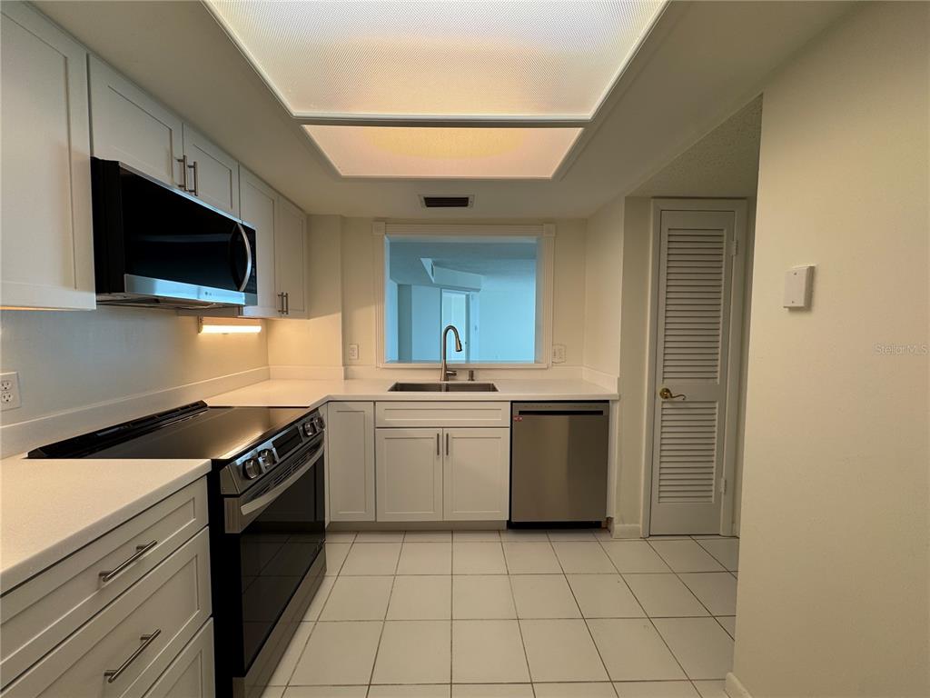 A kitchen features white cabinets, stainless steel appliances, white countertops, and white tile flooring — 2611 BAYSHORE BOULEVARD UNIT 1805, TAMPA, FL