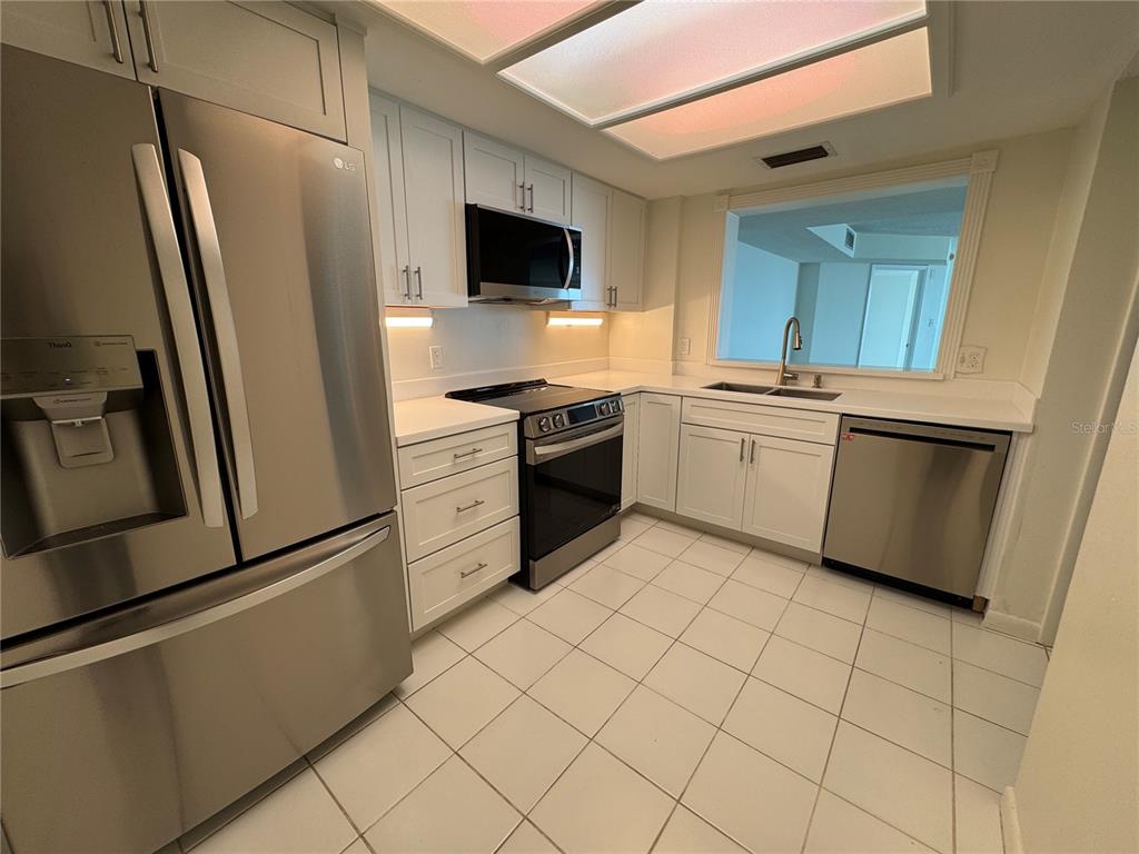 A kitchen features white cabinets, stainless steel appliances, and white tile flooring — 2611 BAYSHORE BOULEVARD UNIT 1805, TAMPA, FL