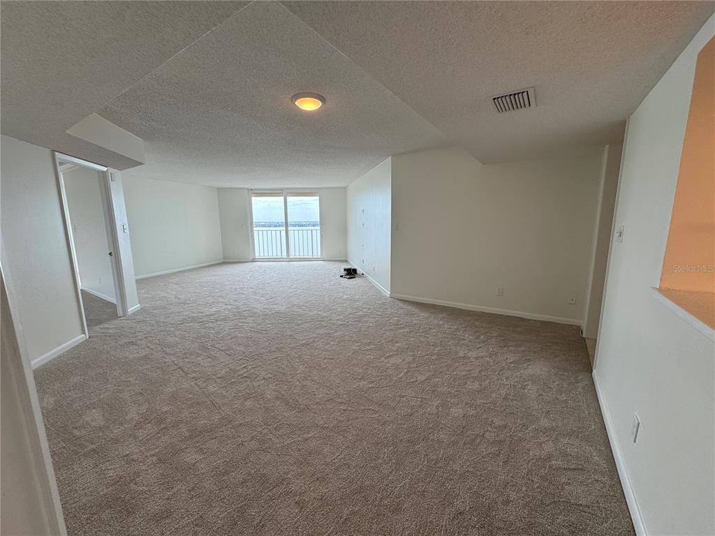 An empty, carpeted living area features white walls, a ceiling light, and a balcony door — 2611 BAYSHORE BOULEVARD UNIT 1805, TAMPA, FL