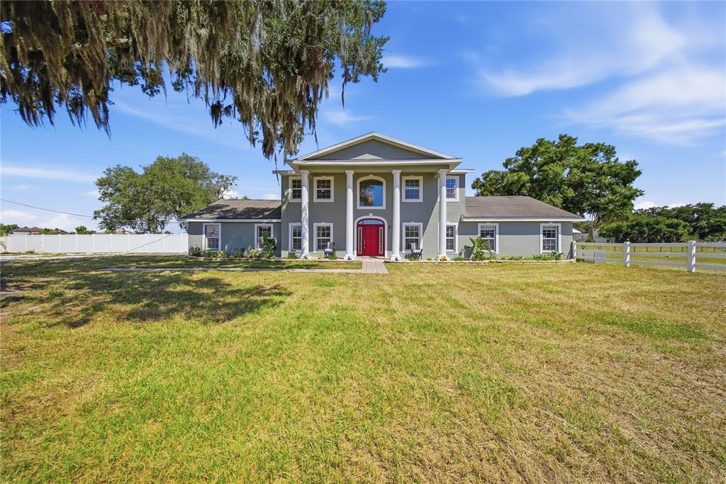 A two-story house with a gray exterior, white columns, and a bright red front door — 13112 BALM BOYETTE ROAD, RIVERVIEW, FL