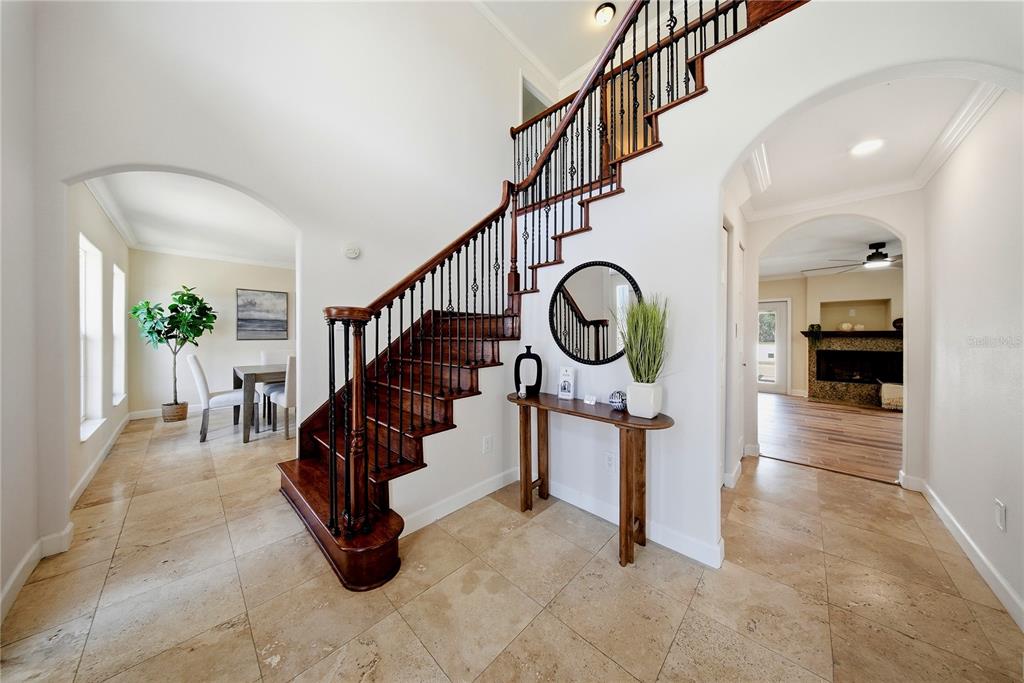 A foyer features a wooden staircase with iron railings, tile flooring, and arched entryways — 13112 BALM BOYETTE ROAD, RIVERVIEW, FL