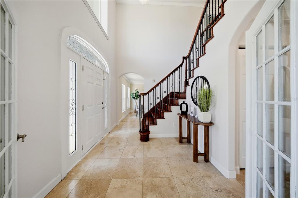 A bright foyer features a curved wooden staircase, tile flooring, and a white front door — 13112 BALM BOYETTE ROAD, RIVERVIEW, FL