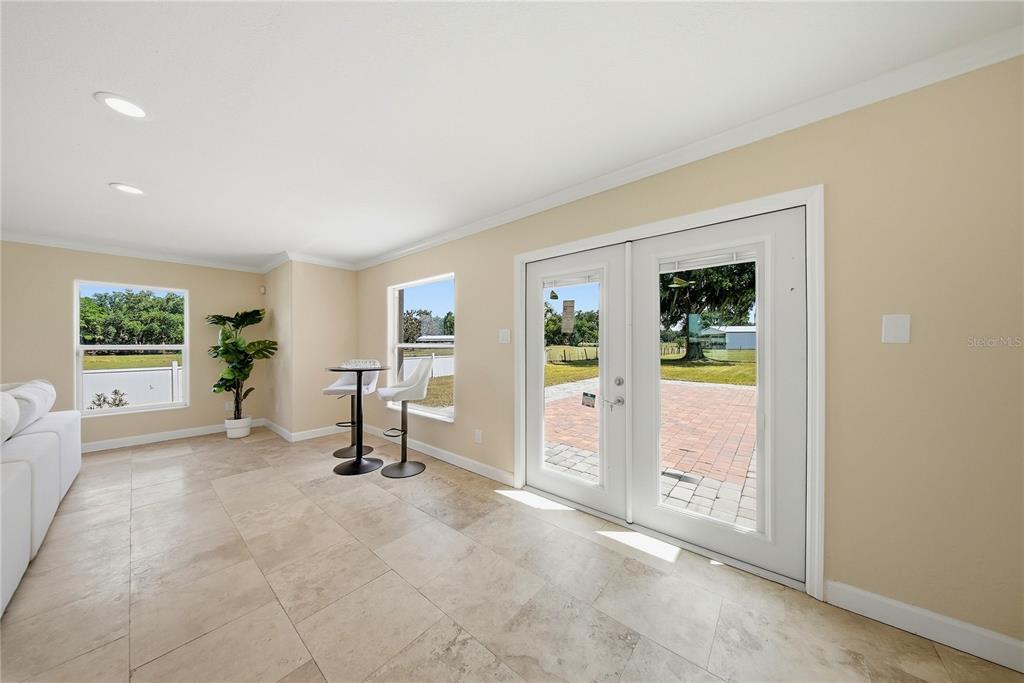 A sunlit room features tile flooring, a small bistro table, and double glass doors — 13112 BALM BOYETTE ROAD, RIVERVIEW, FL